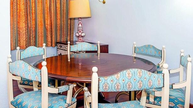Una mesa de comedor redonda de madera rodeada por seis sillas con tapicería estampada.