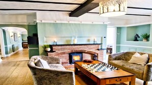 Una sala de estar acogedora con chimenea, asientos cómodos y una mesa de juego de ajedrez.