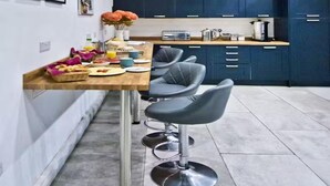 Una cocina con armarios azul oscuro, una encimera de madera y un taburete de bar.