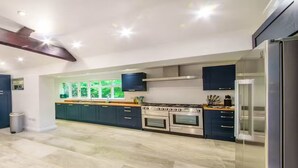 Cocina moderna con armarios oscuros, electrodomésticos de acero inoxidable y un amplio ventanal con vistas a zonas verdes.