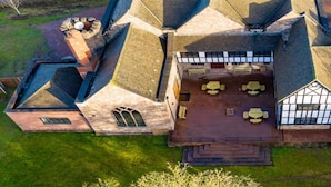 Vista aérea de un edificio grande de varios pisos con un patio central destacado, múltiples chimeneas y una combinación de ladrillo y piedra.