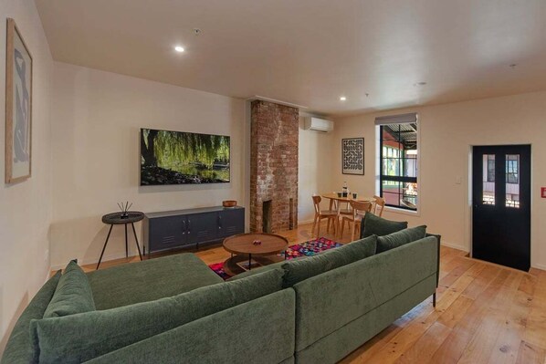 Una sala de estar moderna con un sofá verde, una mesa de centro redonda y una chimenea.
