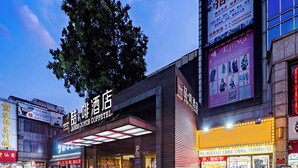 A modern hotel with a prominent sign, outdoor seating area, and adjacent shops. - ELITE James Joyce Coffetel Guangzhou  (Guangzhou)