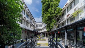 A wooden bridge connecting two buildings with traditional Chinese architectural elements, including tiled roofs and red lanterns. - ELITE James Joyce Coffetel Guangzhou  (Guangzhou)