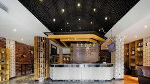 A reception area with a marble floor, a reception desk, and a brick wall with a guitar. - ELITE James Joyce Coffetel Guangzhou  (Guangzhou)