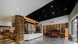A spacious lobby with a central reception desk, a seating area with a fireplace, and a large bookshelf. - ELITE James Joyce Coffetel Guangzhou  (Guangzhou)