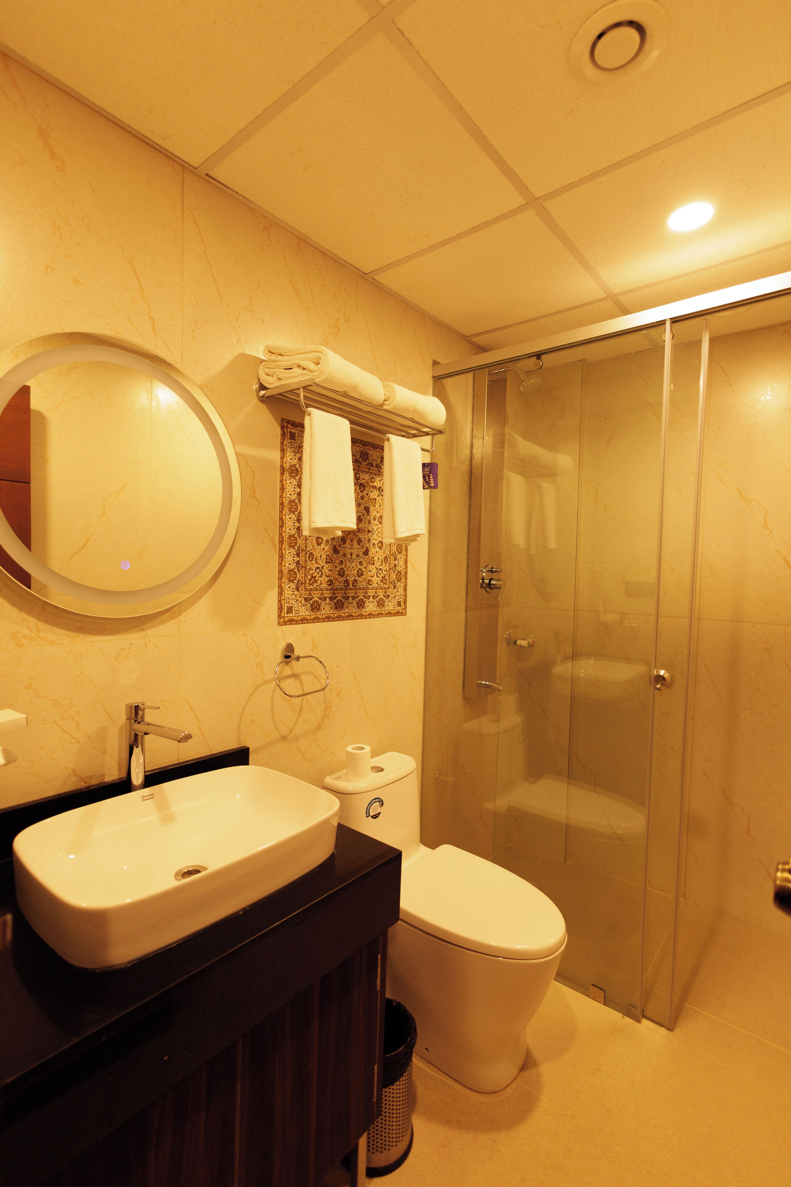 A bathroom with a sink, toilet, and glass shower stall.