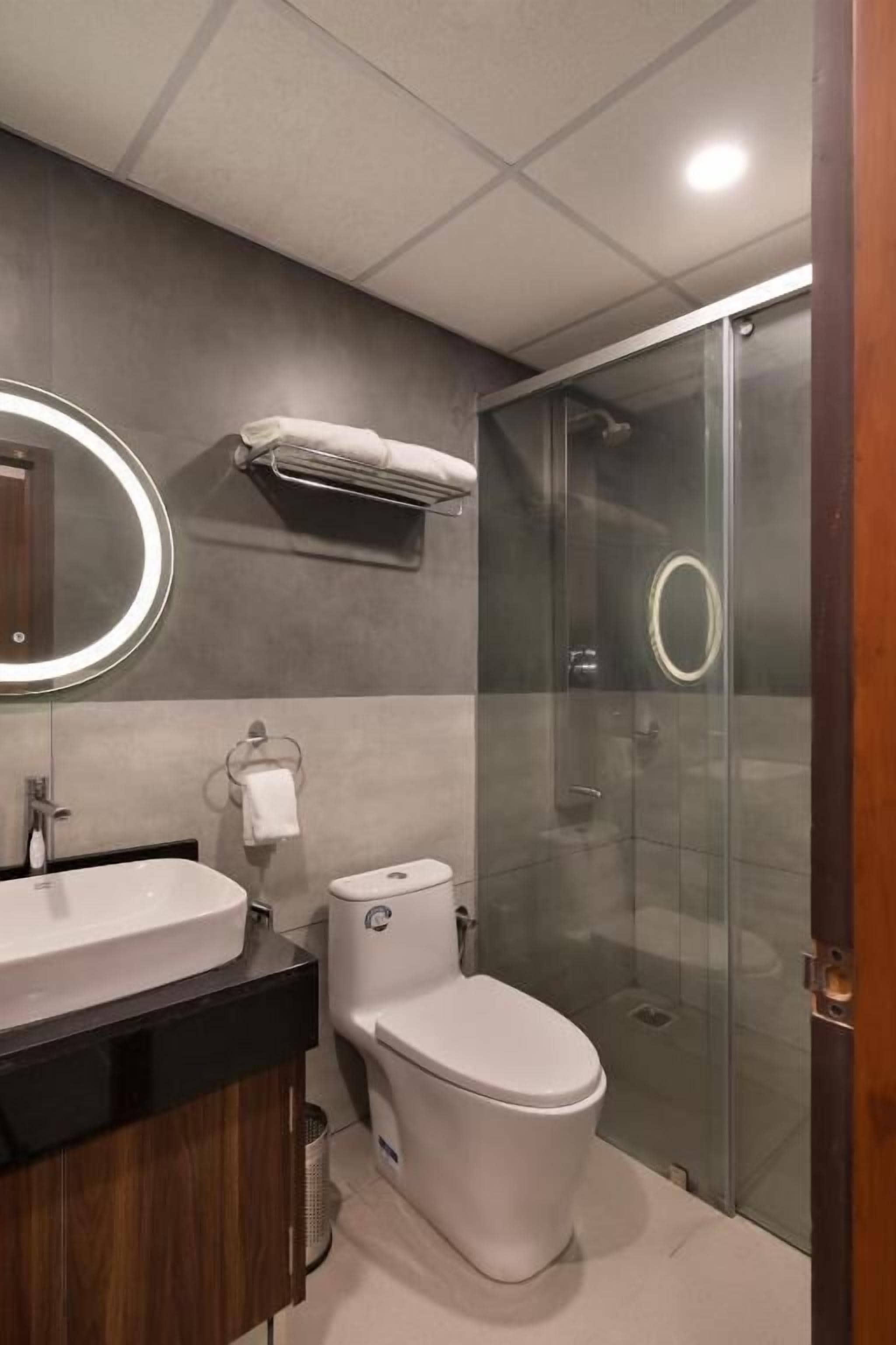 Un bagno moderno con doccia vetrata, un water bianco e un mobile lavabo con specchio.