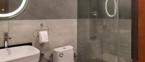 Un bagno moderno con doccia vetrata, un water bianco e un mobile lavabo con specchio.