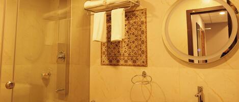 A bathroom with a glass-enclosed shower, a toilet, a sink, and a mirror.