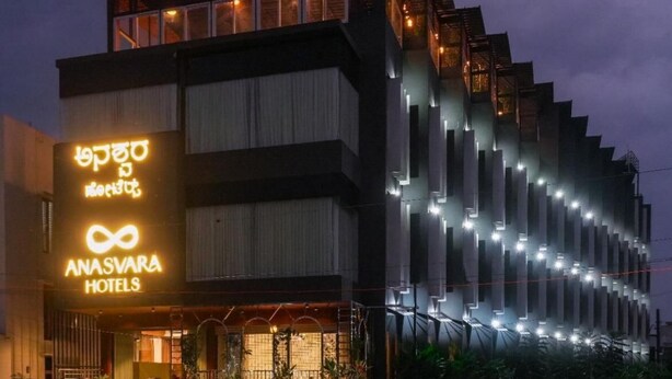 A hotel with a modern design, featuring a prominent infinity symbol sign, multiple floors, and a well-lit facade. - Anasvara Hotels (Mysore)