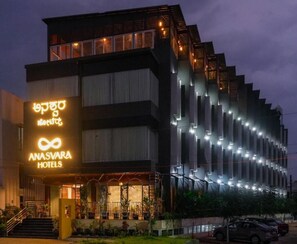 Un hotel de diseño moderno, con un llamativo cartel con forma de símbolo infinito, varios pisos y una fachada bien iluminada.