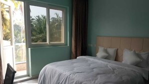A bedroom with a bed, a window, and a view of palm trees. - Anand Vihar Hotel (Ambajipeta)