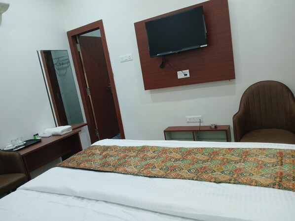 Une chambre d’hôtel comprenant un lit, un téléviseur fixé au mur, un bureau avec un téléphone et une chaise.