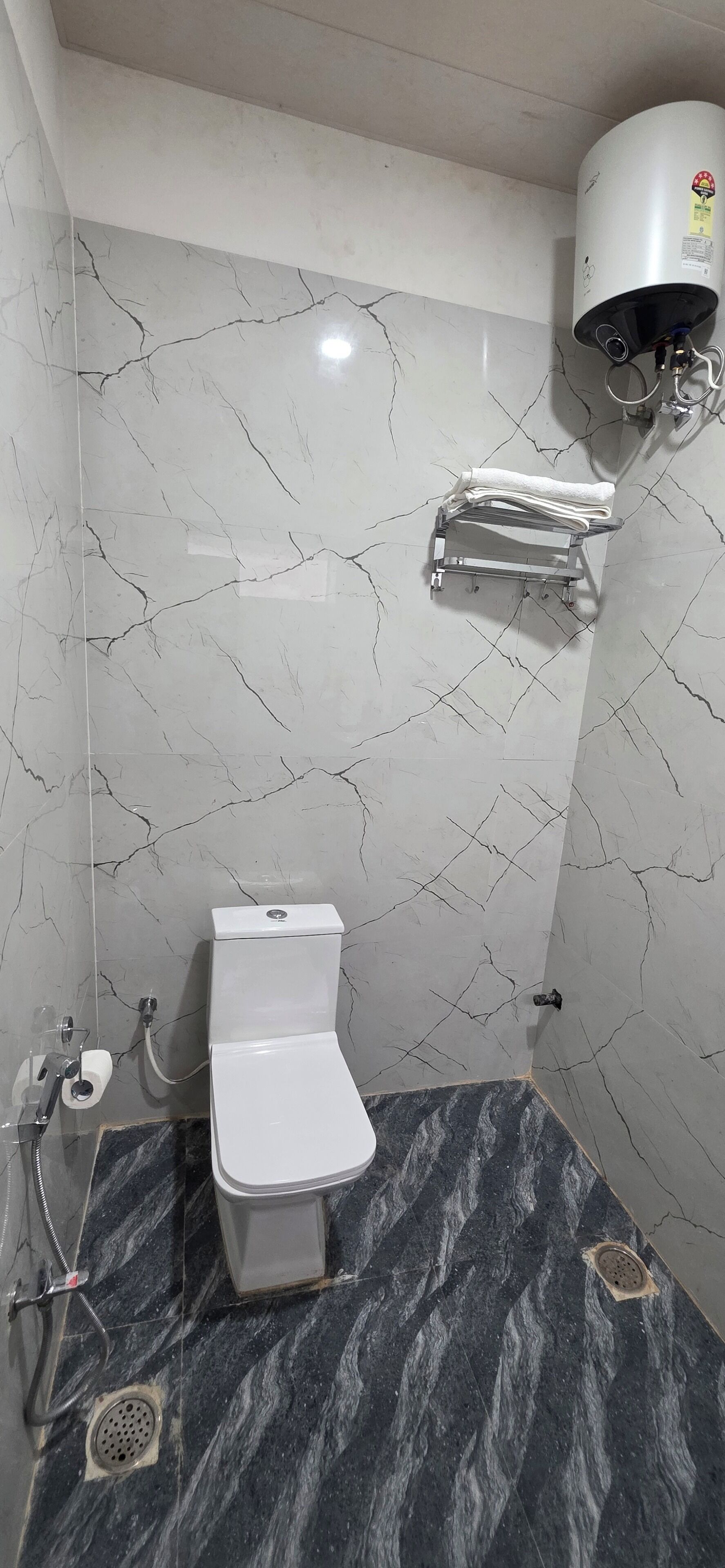 A bathroom with a toilet, a shower, and a towel rack.