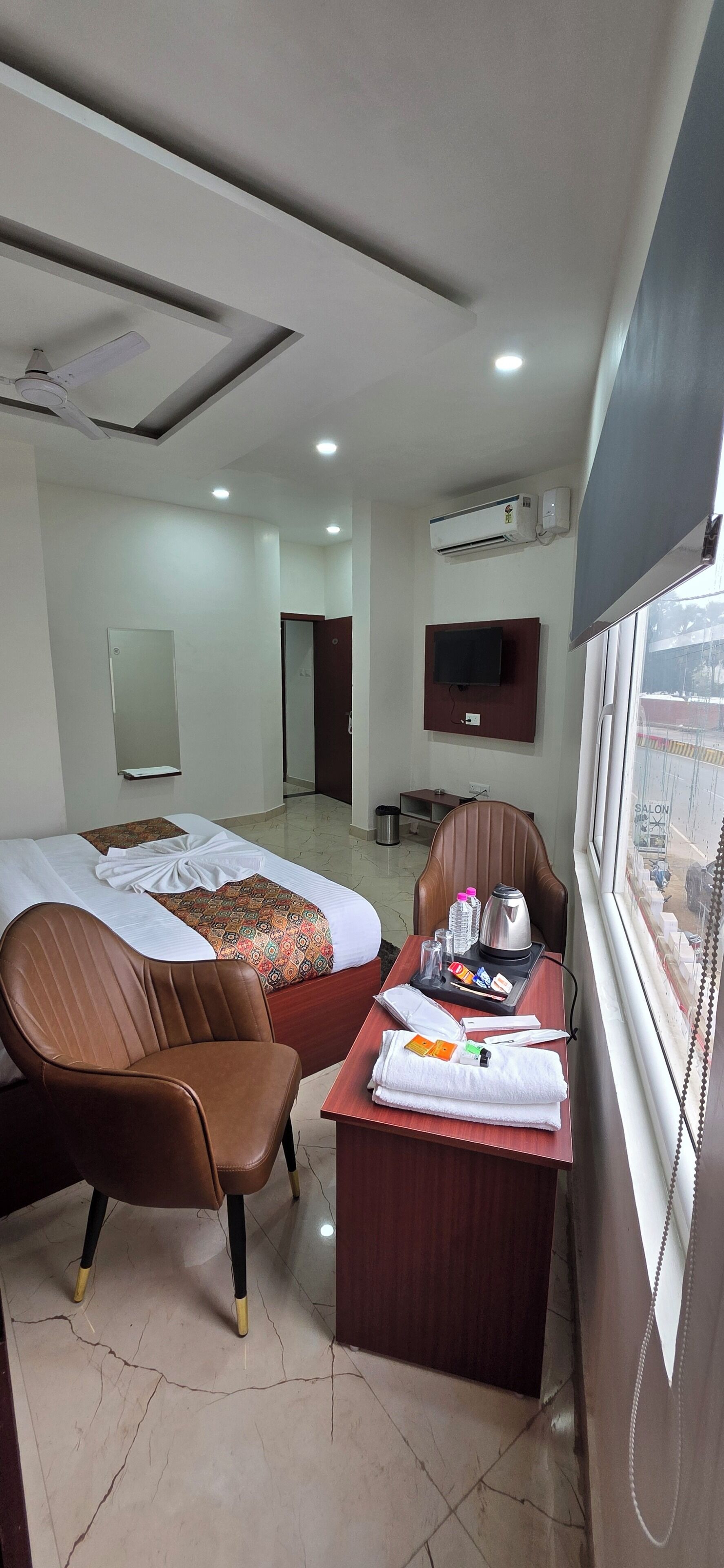 Ein Hotelzimmer mit zwei Betten, einem Schreibtisch mit Pflegeprodukten, einem Fernseher und einer Klimaanlage.