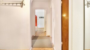 Ein Flur mit einer Holztür, einer weißen Wand und einer Fußmatte am Eingang.