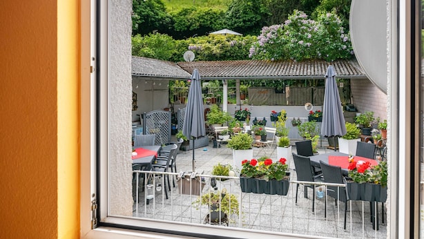 Eine Terrasse mit Sitzgelegenheiten im Freien, Topfpflanzen und Blick auf einen Garten.