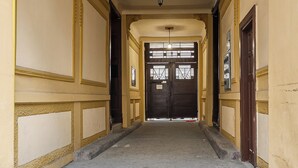 A hallway with a tiled floor, yellow walls, and a dark door at the end. - Lumina bright apart near the city center (Łódź)