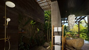 Una ducha de madera con detalles dorados, una pared de piedra con plantas y una escalera de madera con toallas.