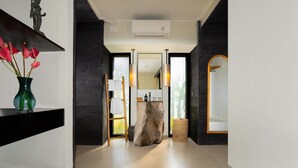 Un pasillo moderno con pared de piedra, un taburete de madera y un espejo.
