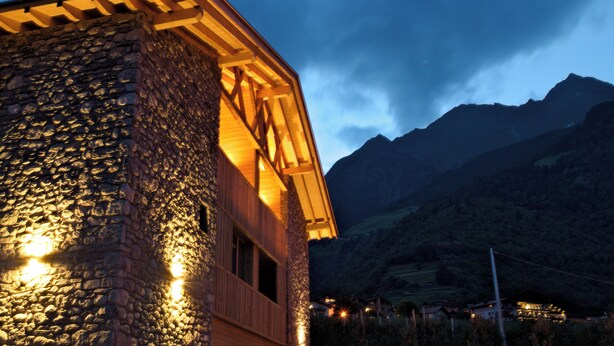 A stone building with wooden beams and a sloped roof, set against a mountainous backdrop. - Apartment in a fantastic location surrounded by greenery on our organic apple farm (Partschins)