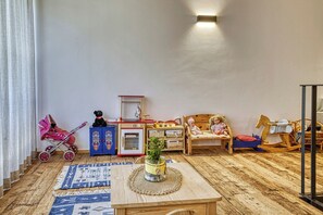 A cozy room with a wooden floor, a small table with a plant, a dollhouse, and a rocking horse. - Apartment in a fantastic location surrounded by greenery on our organic apple farm (Partschins)