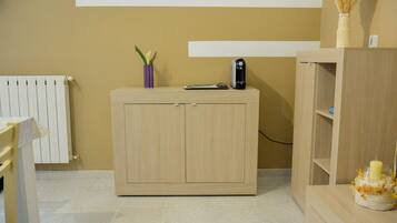A room with a wooden cabinet, a radiator, and a shelf with a candle.