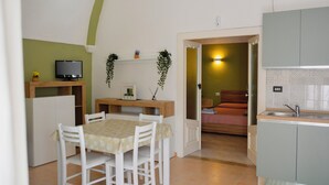 A compact kitchen with a dining area, a television on a shelf, and a small plant. - Casa Mimì (Montemilone)