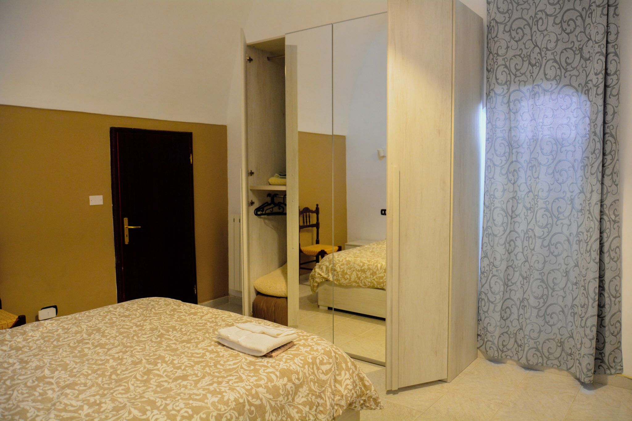 Una habitación de hotel con cama, armario y espejo.