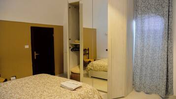 Una habitación de hotel con cama, armario y espejo.