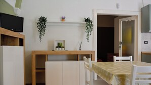 A compact dining area with a wooden table and chairs, a small cabinet, and two hanging plants. - Casa Mimì (Montemilone)