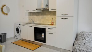 A compact kitchen with a washing machine, oven, and a sink. - Casa Mimì (Montemilone)