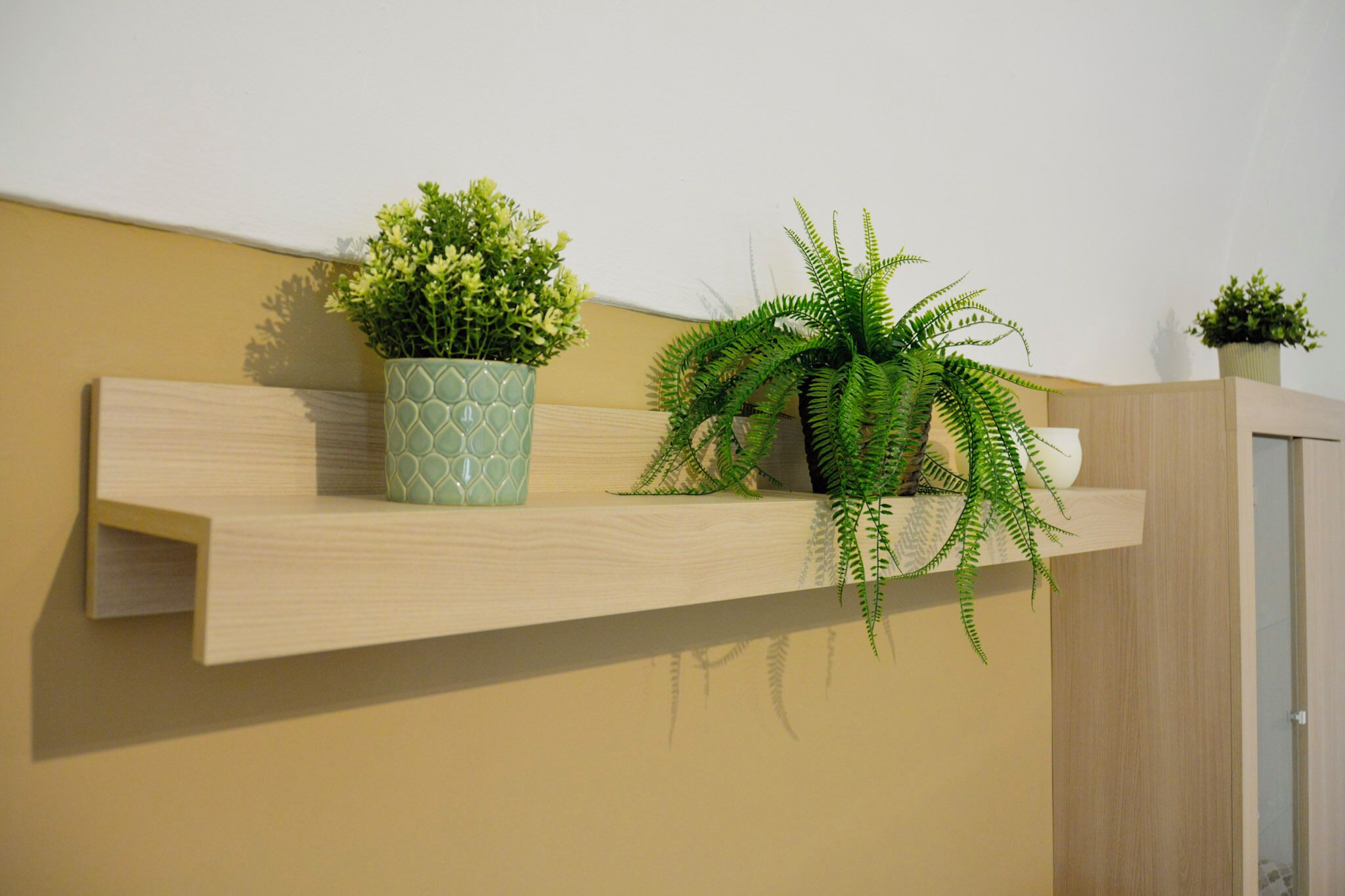 Ein Holzregal mit zwei Blumentöpfen vor einer Wand.