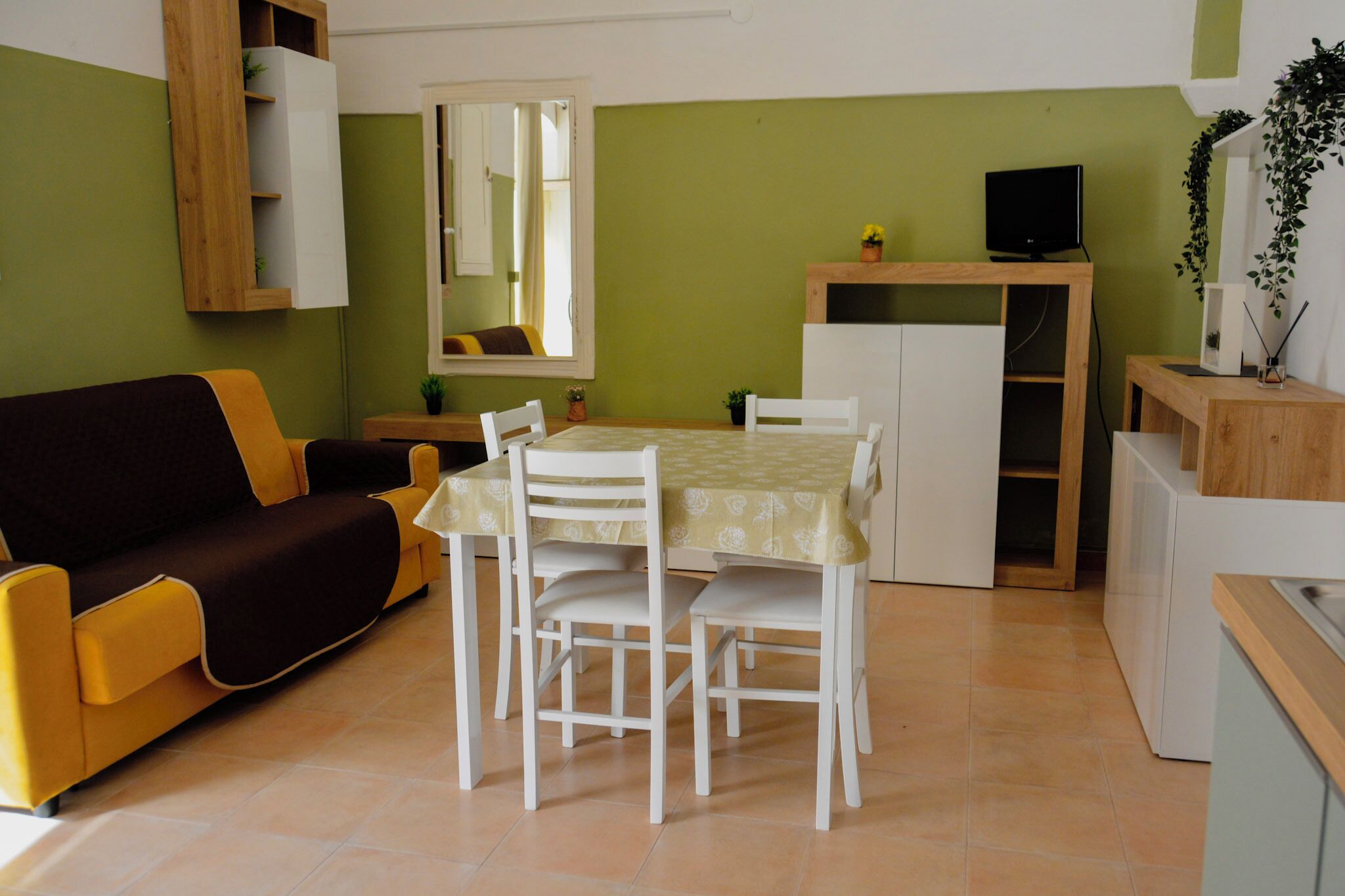Um espaço compacto com sofá, mesa de jantar, cadeiras, televisão e armário.