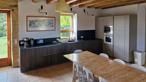 Una cocina moderna con vigas de madera, una mesa de comedor y vistas a la vegetación.