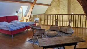 Un dormitorio tipo loft acogedor con cama roja, mobiliario de mimbre y una mesa de madera.