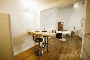 Eine moderne Küche mit Holztisch und Barhocker, einem weißen Kühlschrank und einer Pendelleuchte.