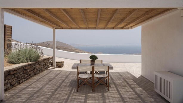 Un espace extérieur abrité, avec une table et des chaises, donnant sur une plage.