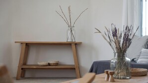 Un salon minimaliste avec une table en bois, un vase en verre orné de branches et un canapé avec des coussins.