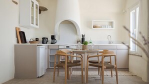 Une cuisine moderne dotée d’un îlot central, de meubles blancs et d’une arche en pierre rustique.