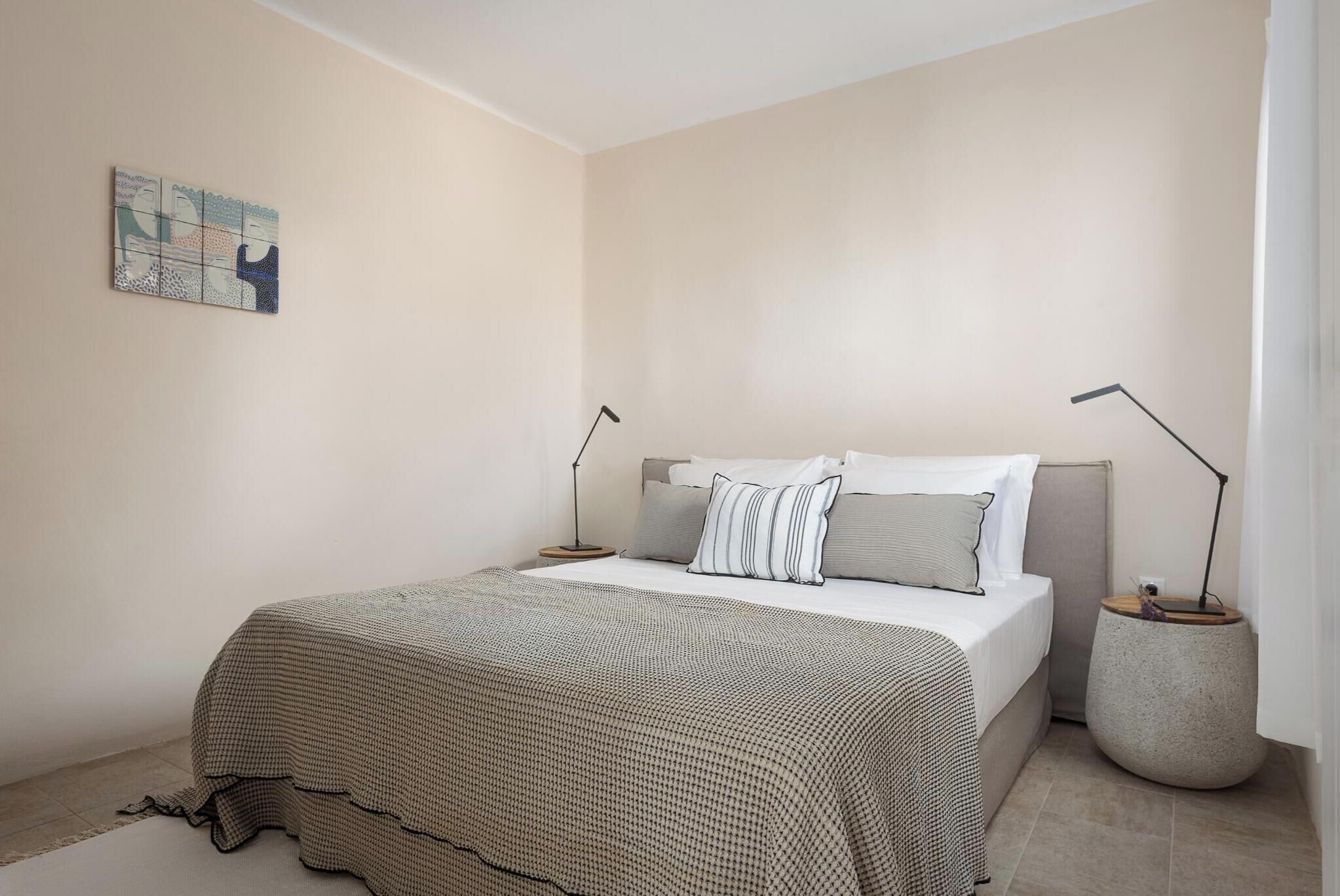 Une chambre à coucher comprenant un lit, des tables de chevet et une œuvre d’art murale.