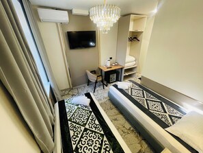 A hotel room with a bed, a desk, a chair, a TV, a wardrobe, and a chandelier. - Naya Hotel (Almaty)