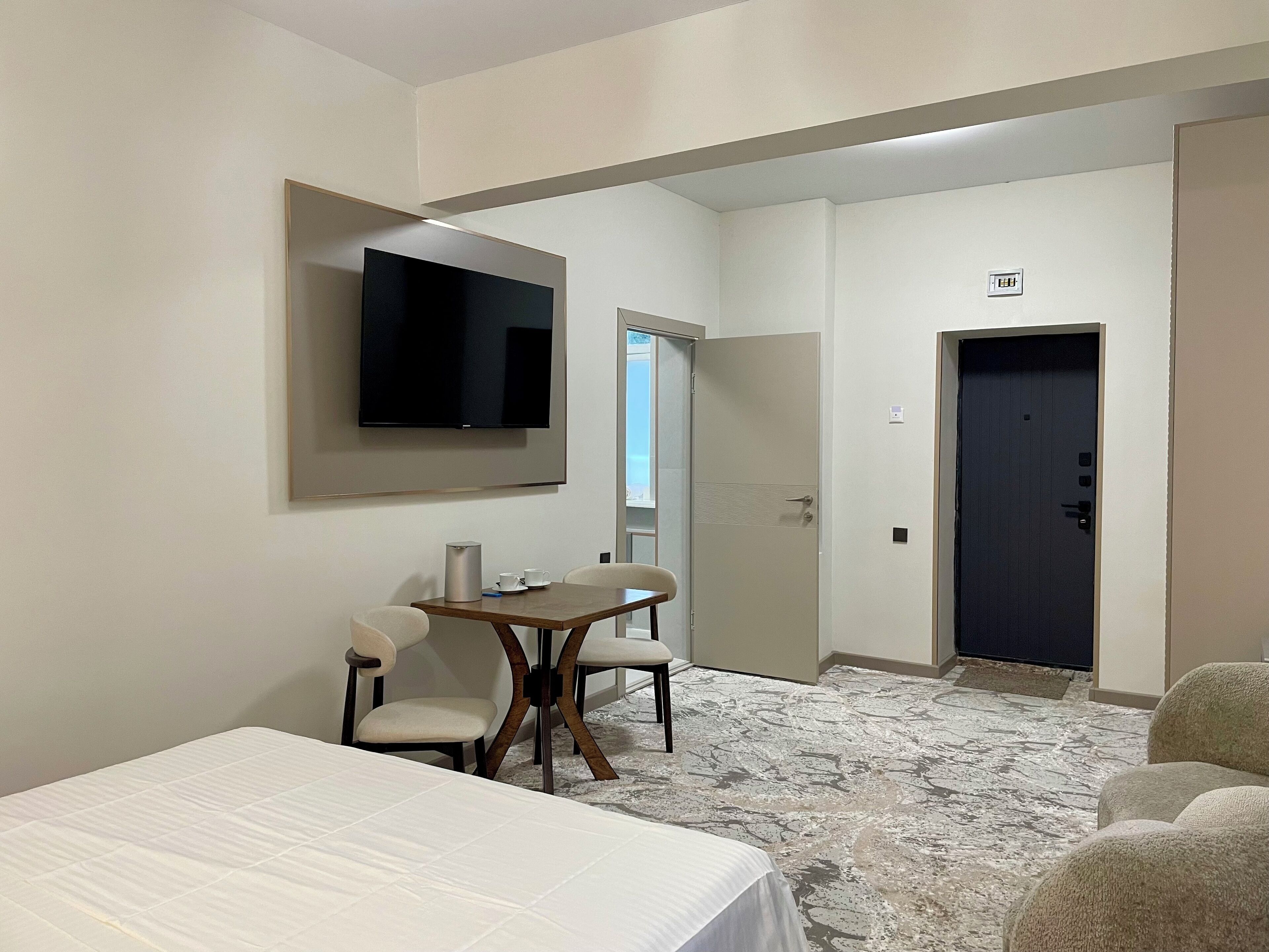 A hotel room with a bed, a desk, a chair, a television, and a door.