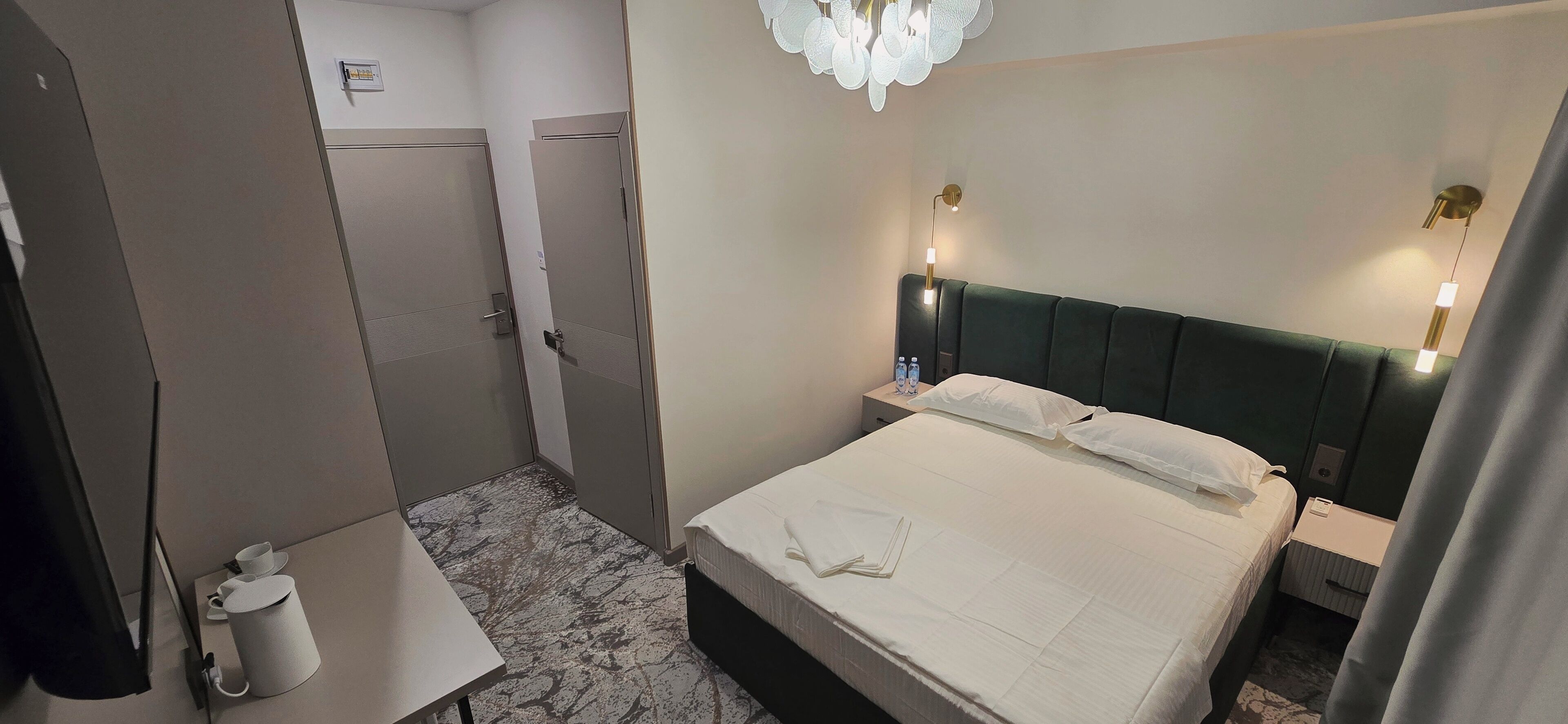 Une chambre d’hôtel avec un lit, une table de chevet et une petite table sur laquelle se trouvent une tasse et une soucoupe.