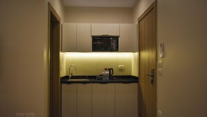A compact kitchen with a microwave, sink, and cabinets. - Stay Inn51 Al Sheikh Zayed (Giza Governorate)
