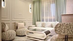 A modern living room with a white sofa, patterned ottomans, and a glass coffee table. - Stay Inn51 Al Sheikh Zayed (Giza Governorate)