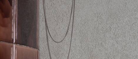 A textured wall with a double-layered chain hanging from it.