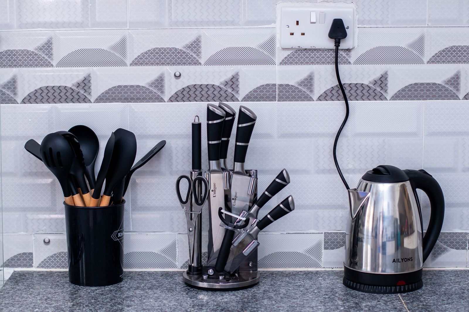 A kitchen counter with a coffee maker, a utensil holder, and a pair of scissors.