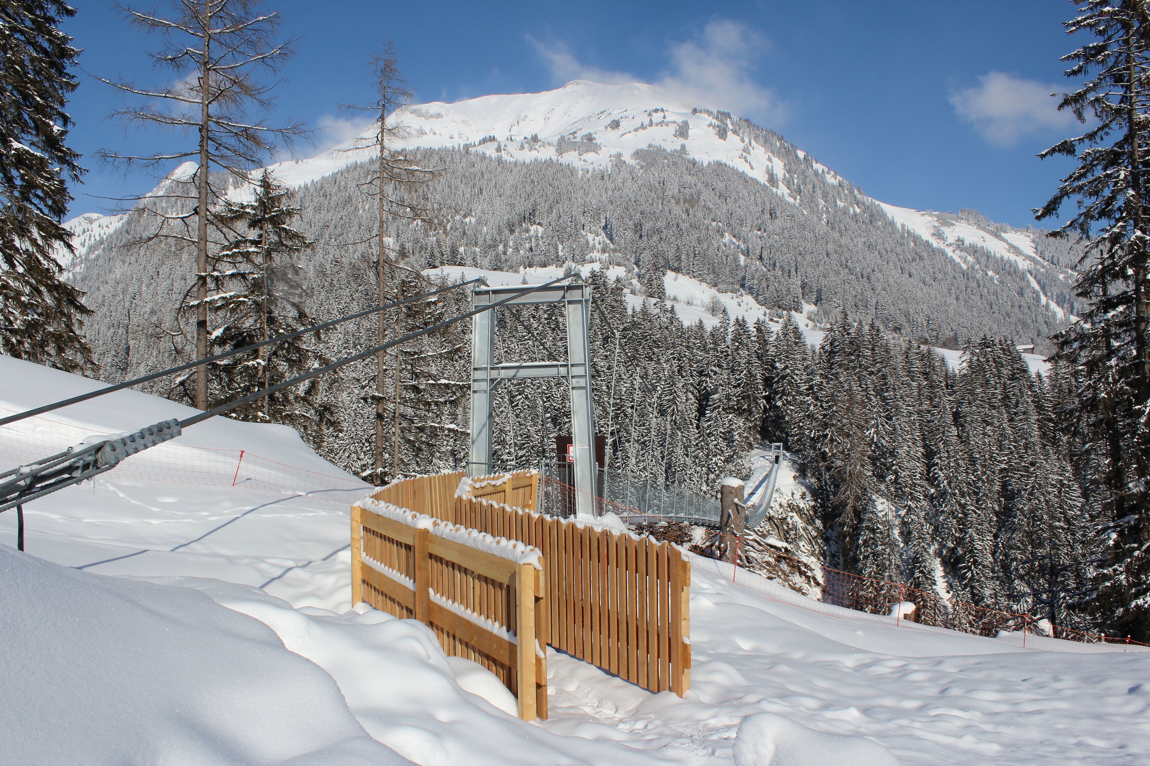 A snow-covered mountain with a wooden fence and a metal structure in the foreground.